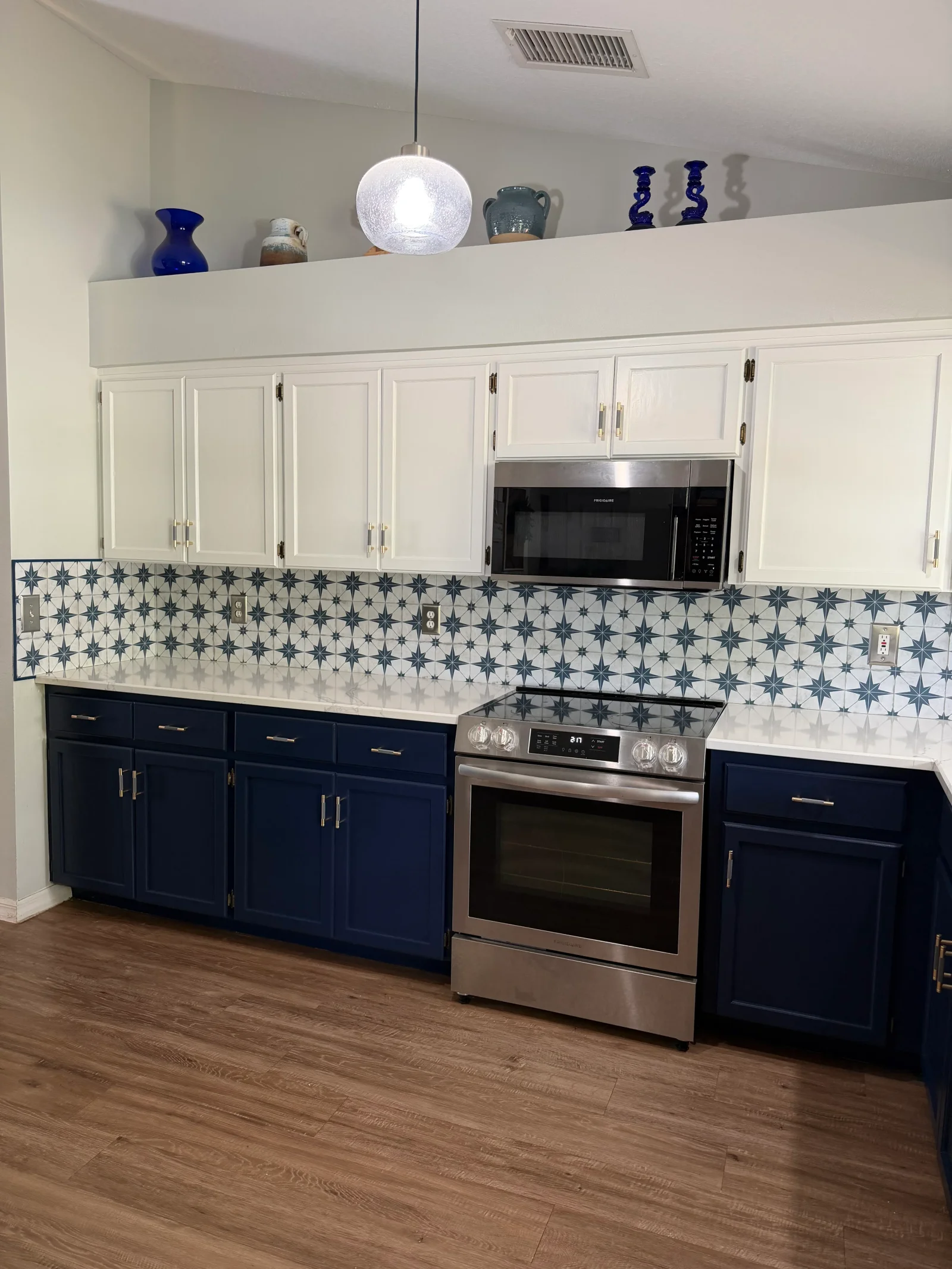 Navy and white two-tone kitchen cabinets with star-pattern tile backsplash and quartz counters