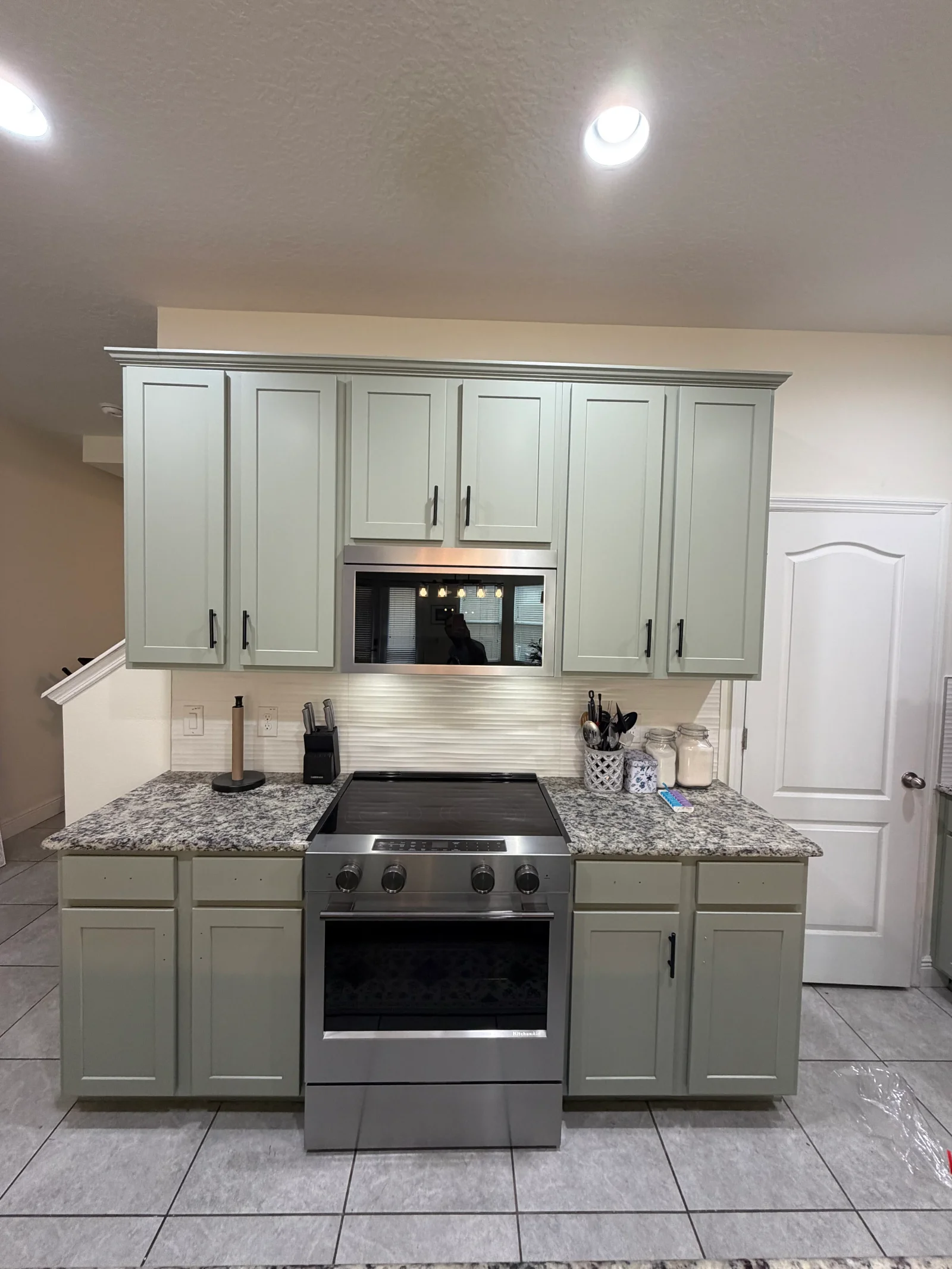 Sage green painted kitchen cabinets with white subway tile backsplash and granite countertops