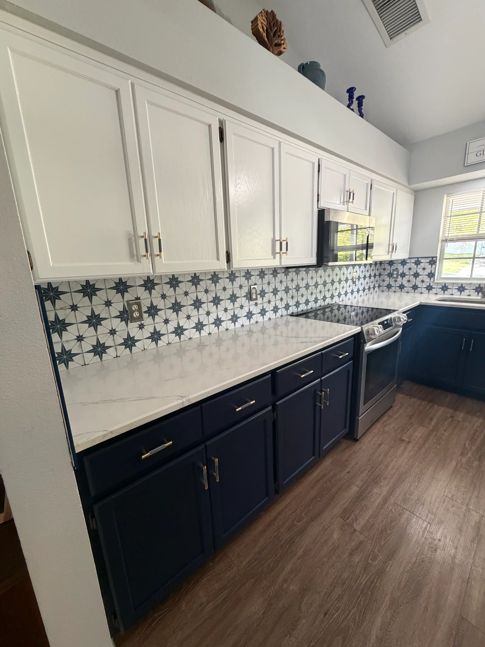 Two-tone kitchen with white upper and navy lower cabinets, star tile backsplash, white countertops