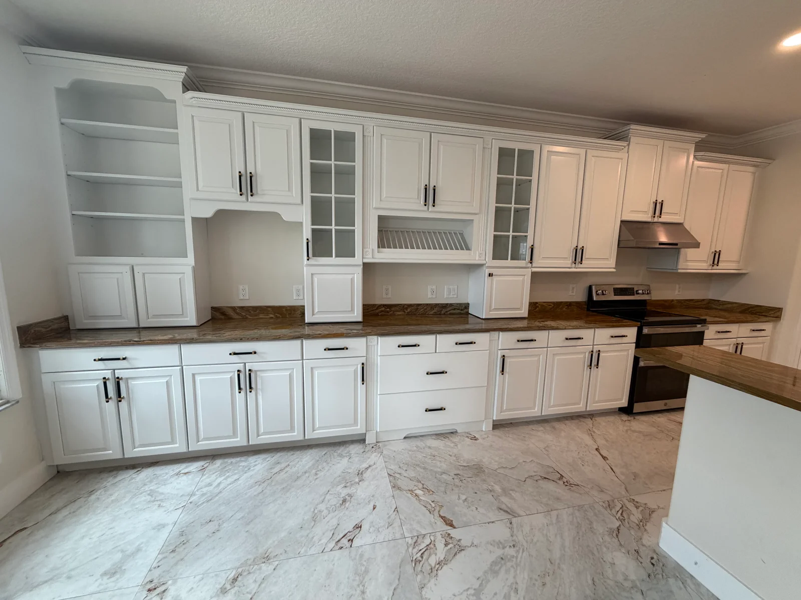 White painted kitchen cabinets with dark wood countertops and black hardware