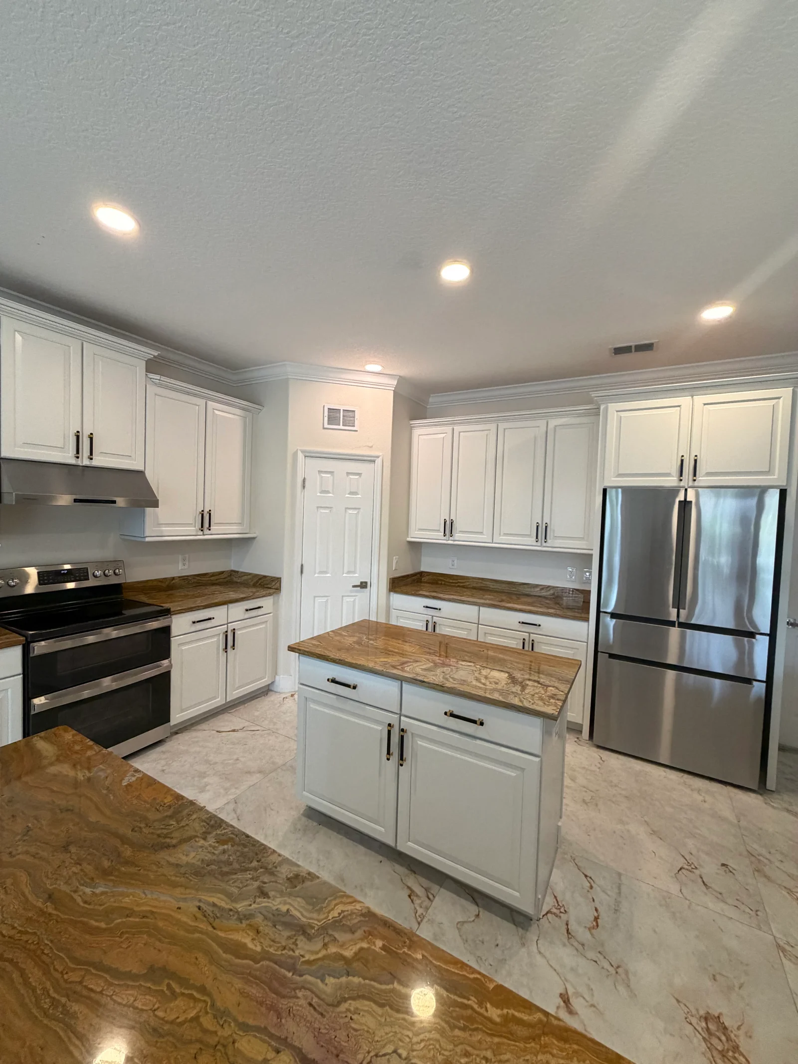 White painted kitchen cabinets with wood countertops, painted ceiling, and recessed lighting