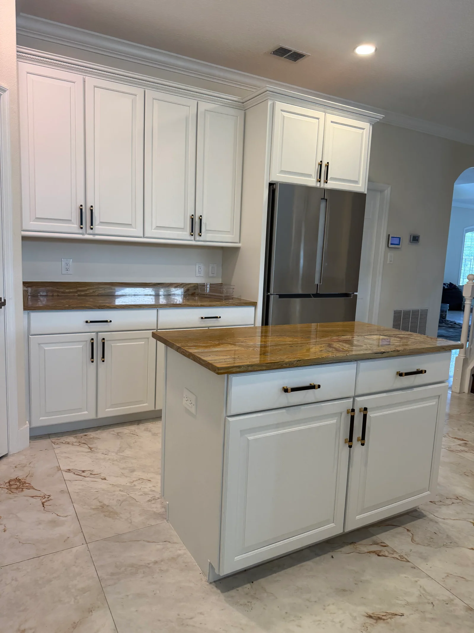 White painted kitchen cabinets with black hardware, wood countertops, and stainless steel appliances